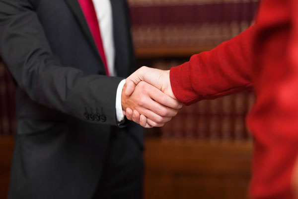 person in red sweater shaking hands with a person in a suit